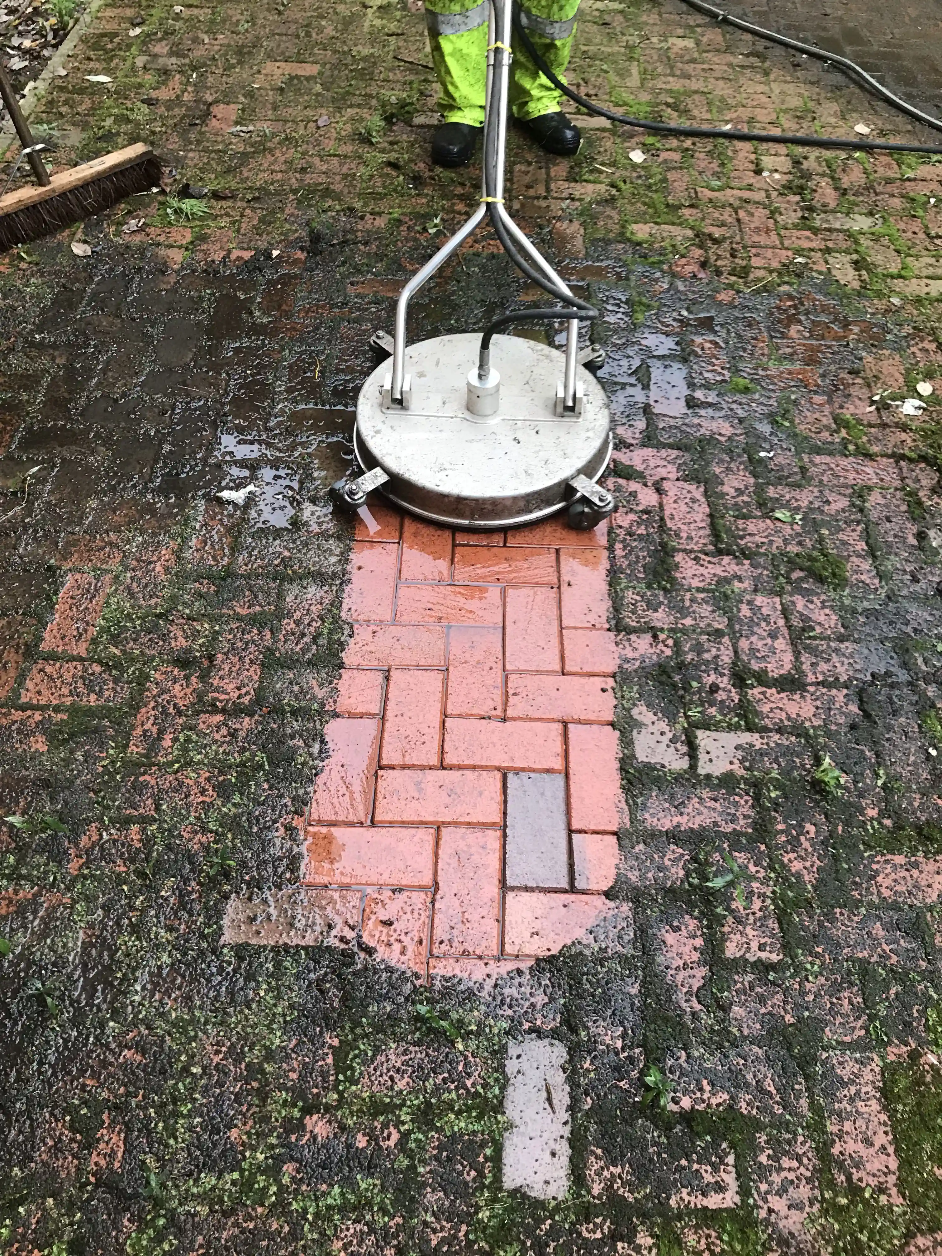 Moss buildup on brick road before pressure washing cleanup