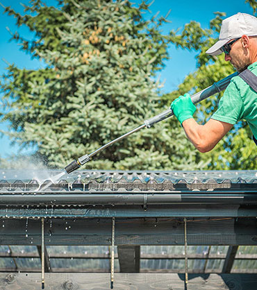 Gutter cleaning service in progress on residential exterior